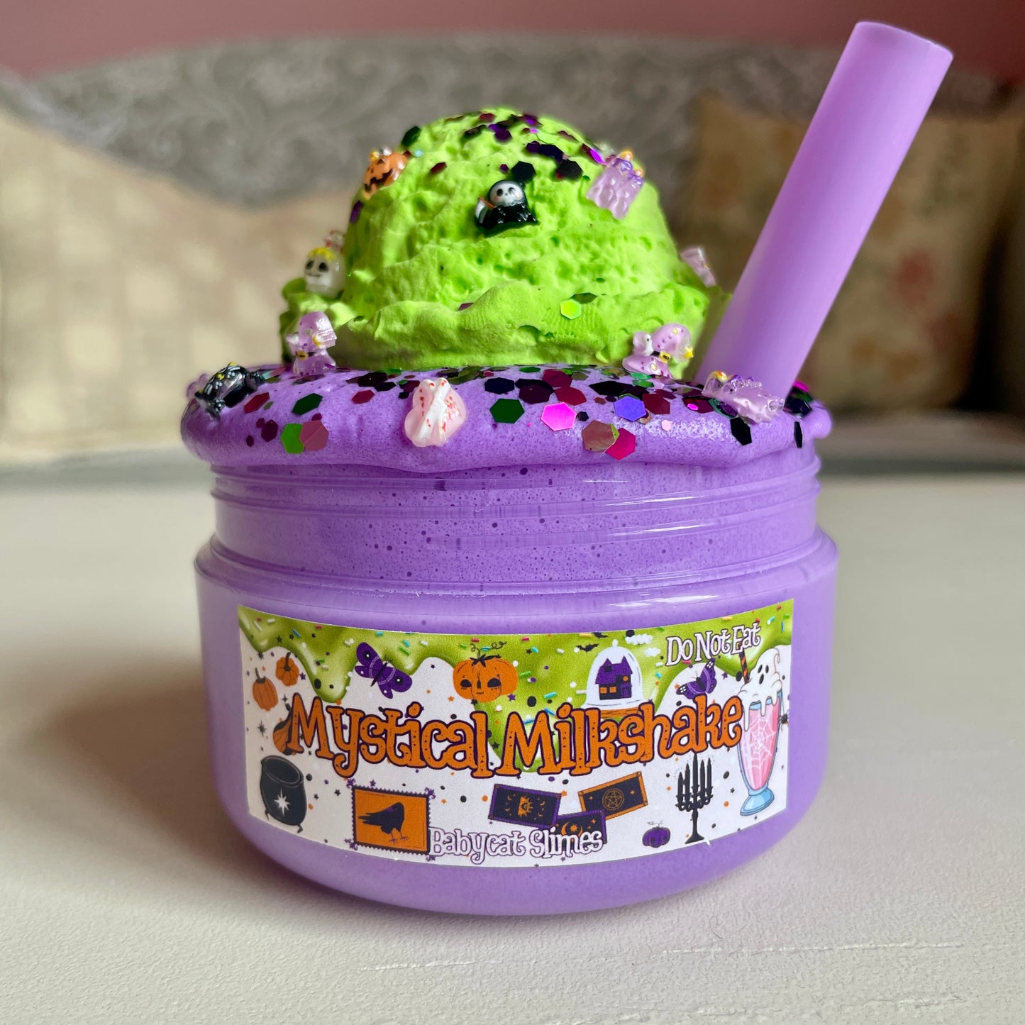 Purple container of slime with green top, labeled 'Mystical Milkshake', on a neutral background.