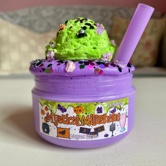 Purple container of slime with green top, labeled 'Mystical Milkshake', on a neutral background.