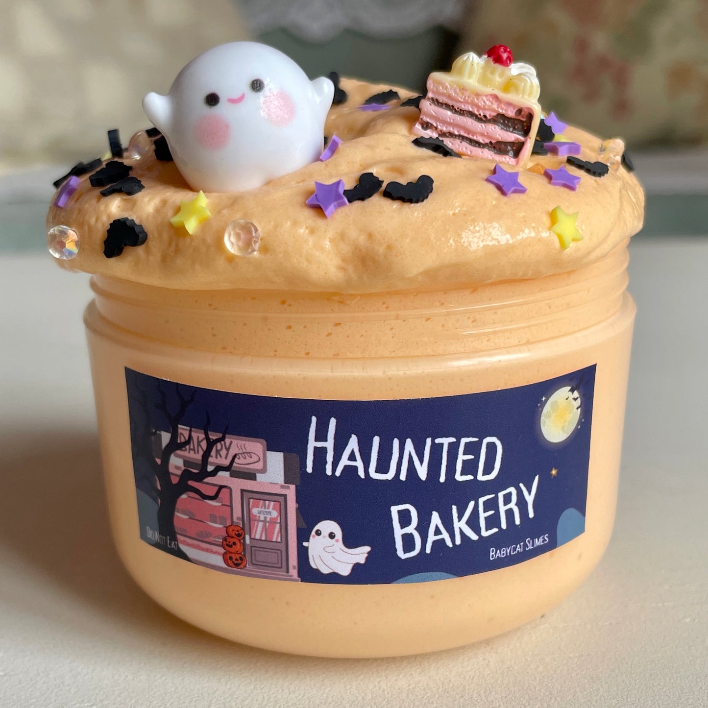 Orange slime with a Halloween-themed label and decorations, including a ghost and cake slice.